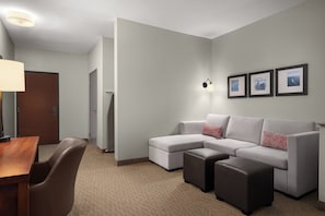 A modern hotel room with a sectional sofa, a small table, and a lamp.
