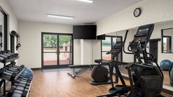 Een fitnessruimte met loopbanden, hometrainers en krachtapparaten.