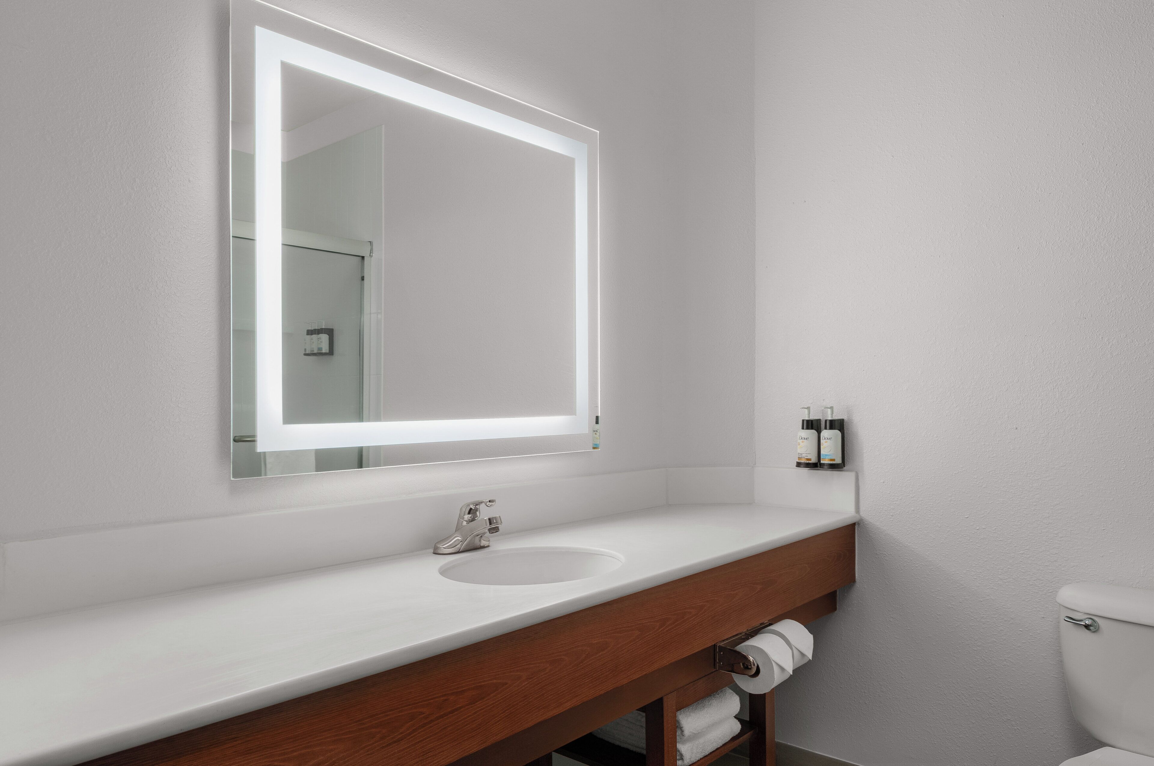 Un baño con lavamanos blanco, espejo y retrete.