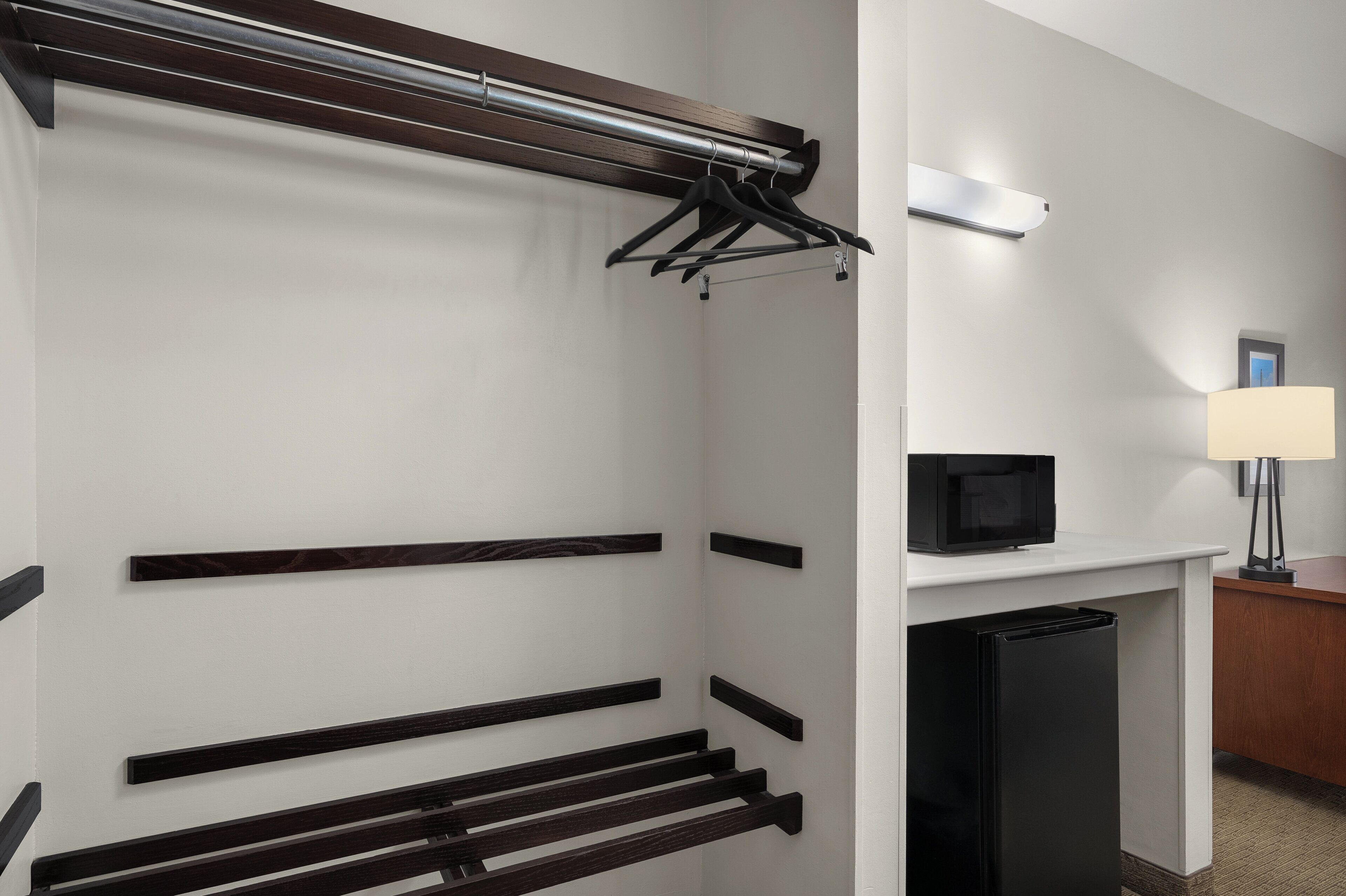 Habitación de hotel con armario empotrado, televisor de pantalla plana y escritorio con lámpara.