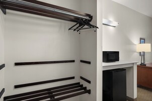 Habitación de hotel con armario empotrado, televisor de pantalla plana y escritorio con lámpara.
