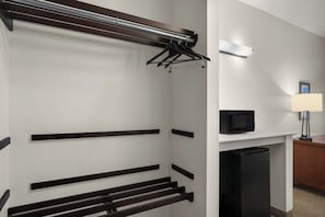 Habitación de hotel con armario empotrado, televisor de pantalla plana y escritorio con lámpara.
