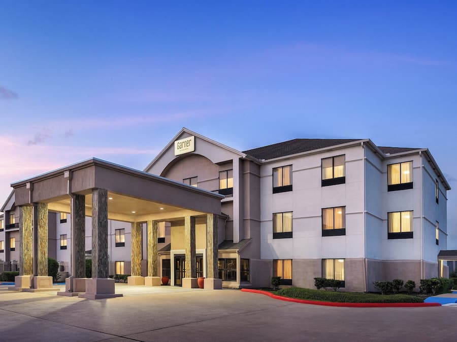 A hotel with a covered entrance, multiple floors, and a clear sky.