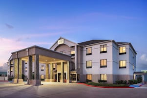 Un hotel con entrada cubierta, varios pisos y cielo despejado.
