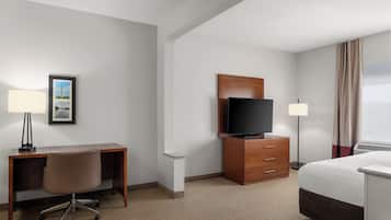 A hotel room with a desk, chair, television, and a bed.
