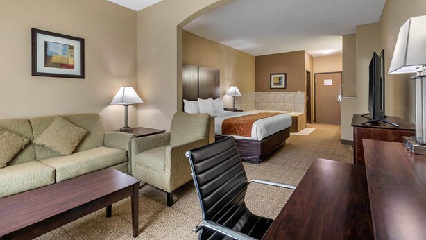 Une chambre d’hôtel équipée d’un canapé, d’un fauteuil, d’une table à manger et d’un lit avec une tête de lit.