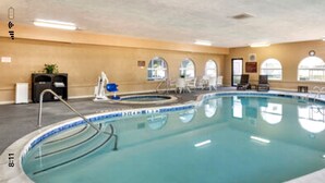 Une grande piscine intérieure dotée de plusieurs couloirs de nage, d’un toboggan et de chaises longues.