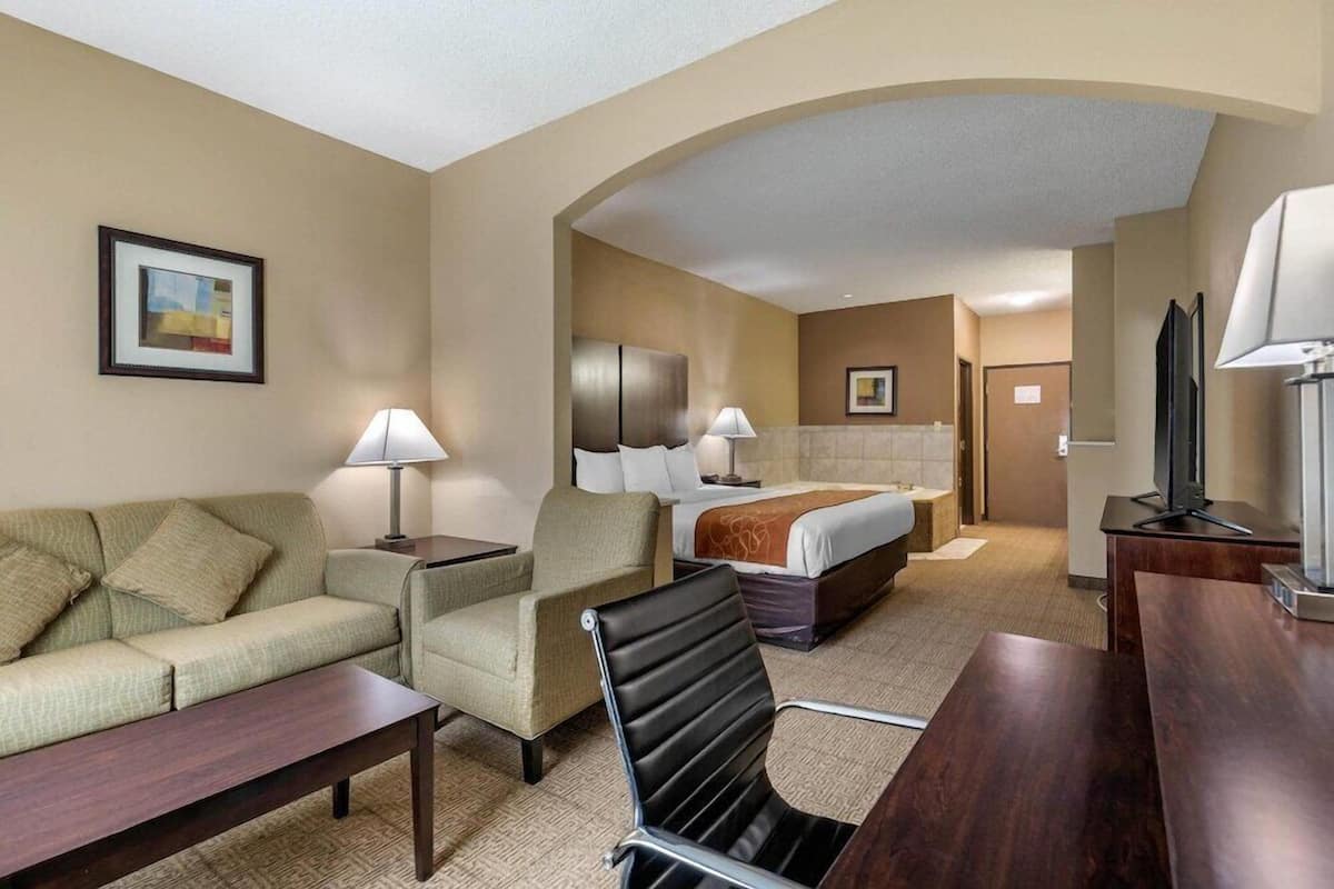 Ein Hotelzimmer mit Sofa, Sessel, Schreibtisch, Bett und Fernseher.