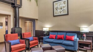 Un salon moderne avec un canapé bleu, des fauteuils rouges et une cheminée.