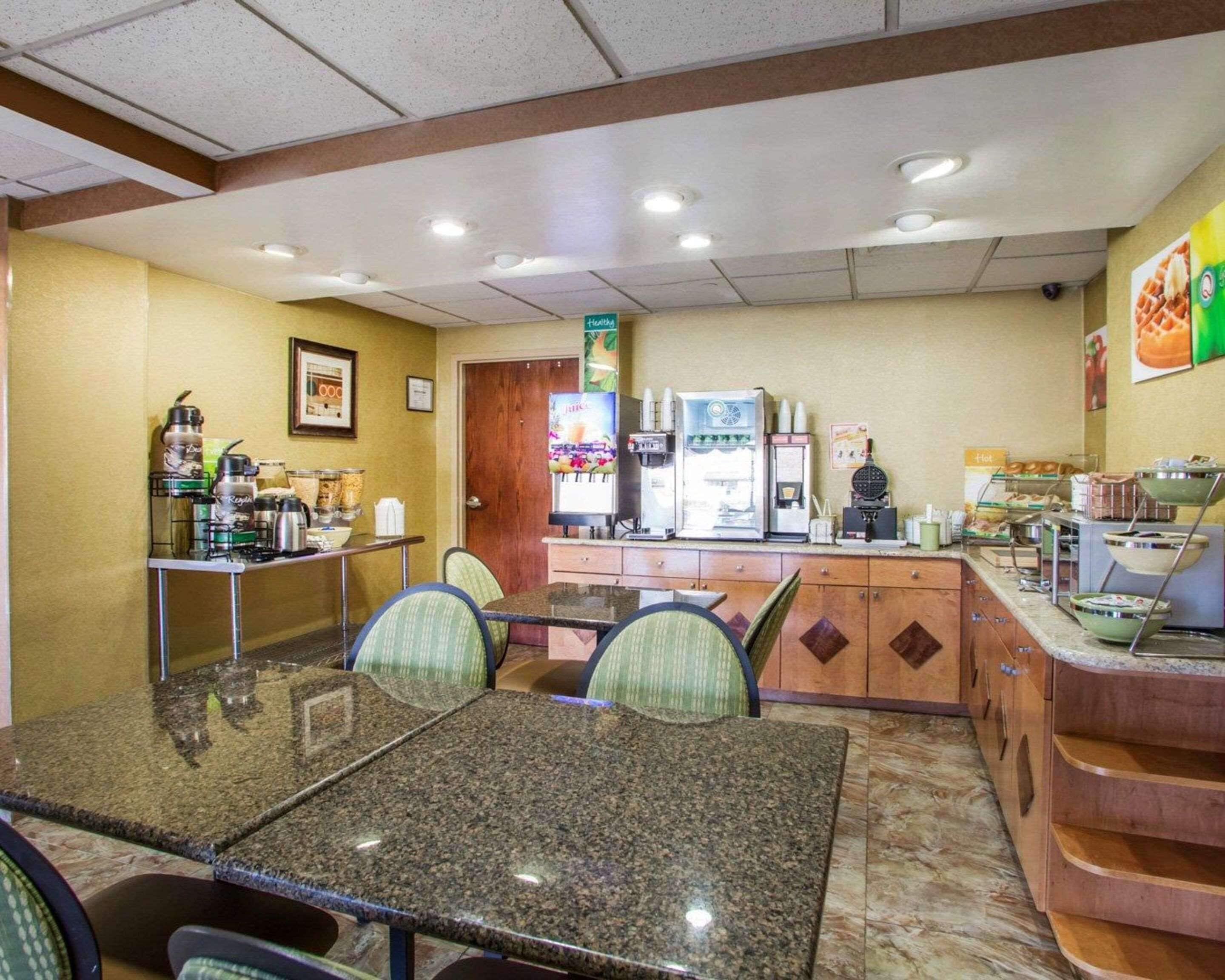 Un restaurant avec une table et des chaises en granit, une machine à café et un réfrigérateur.