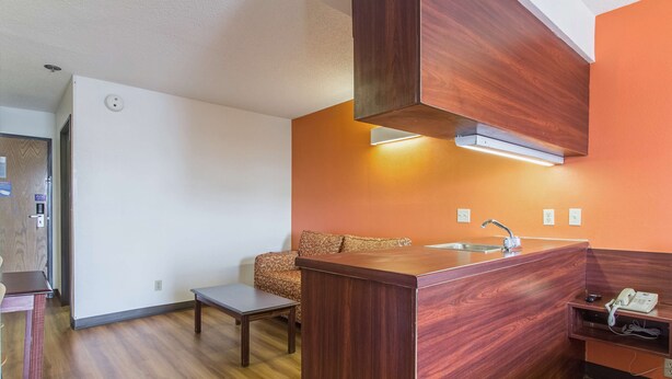 A modern kitchen with a wooden countertop, a built-in sink, and a patterned sofa.