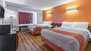 A hotel room with two beds, a TV, a desk, and a window with curtains.