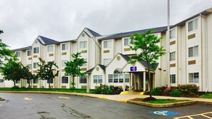 Un hôtel à plusieurs étages doté d’une entrée principale, d’un parking et d’une place de stationnement réservée aux personnes handicapées.