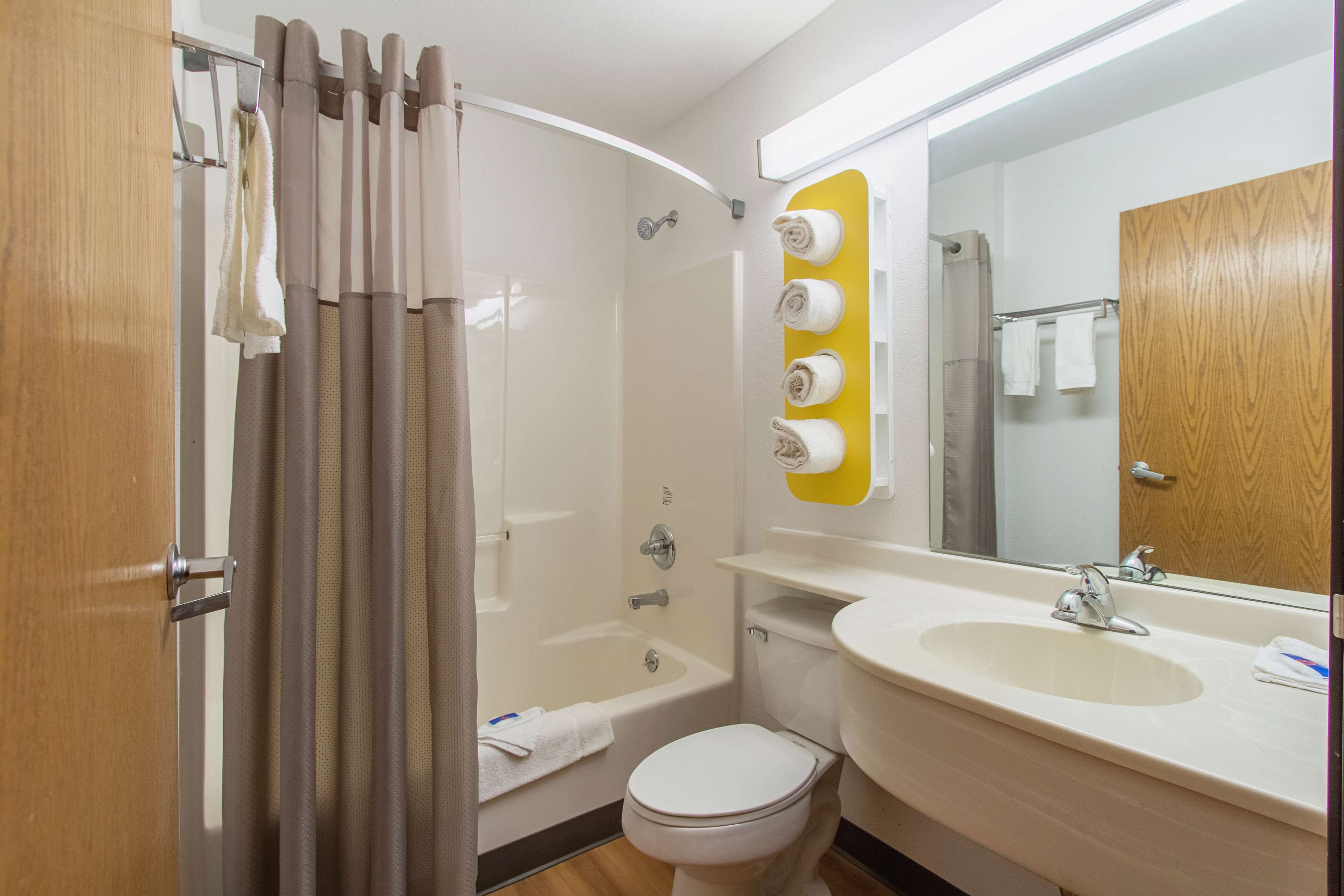 A bathroom with a shower, toilet, sink, and a mirror.