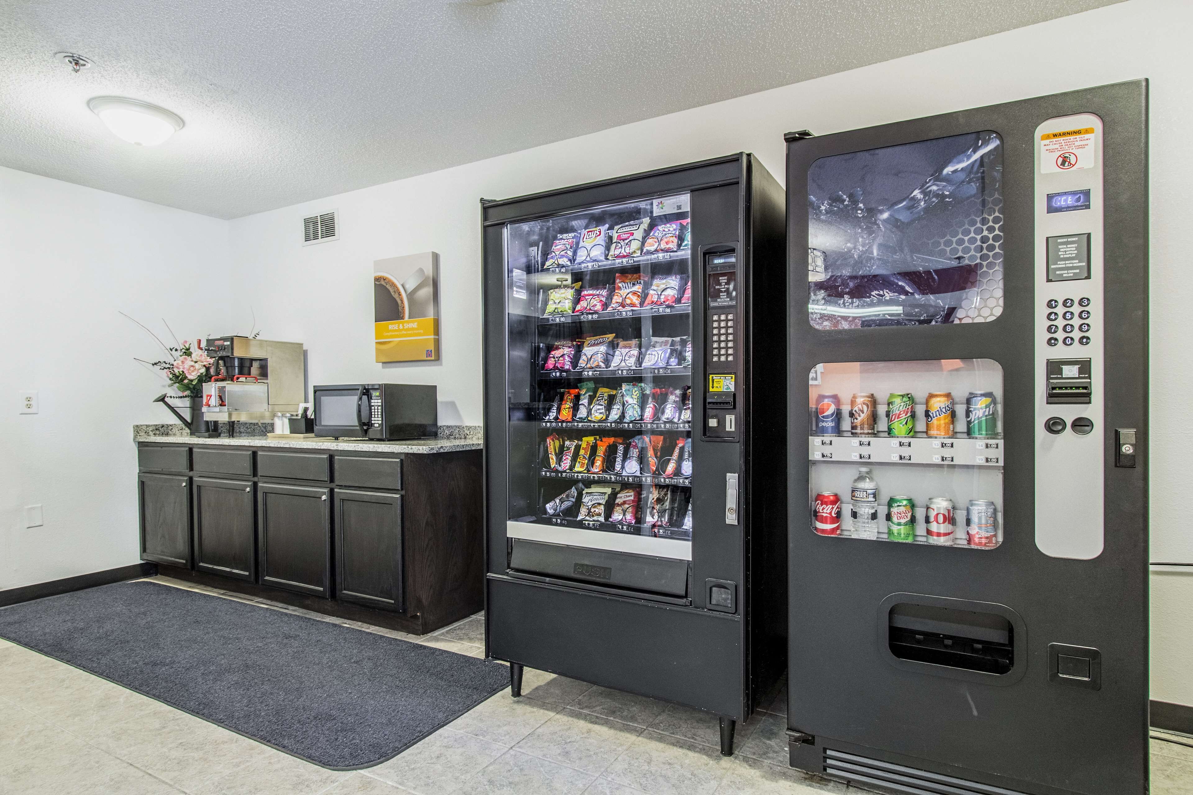 A vending machine with snacks and drinks, a coffee machine, and a small counter with a flower arrangement.
