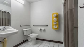Casa de banho com lavatório branco, sanita e cortina de chuveiro. Há um porta-toalhas amarelo com quatro toalhas.