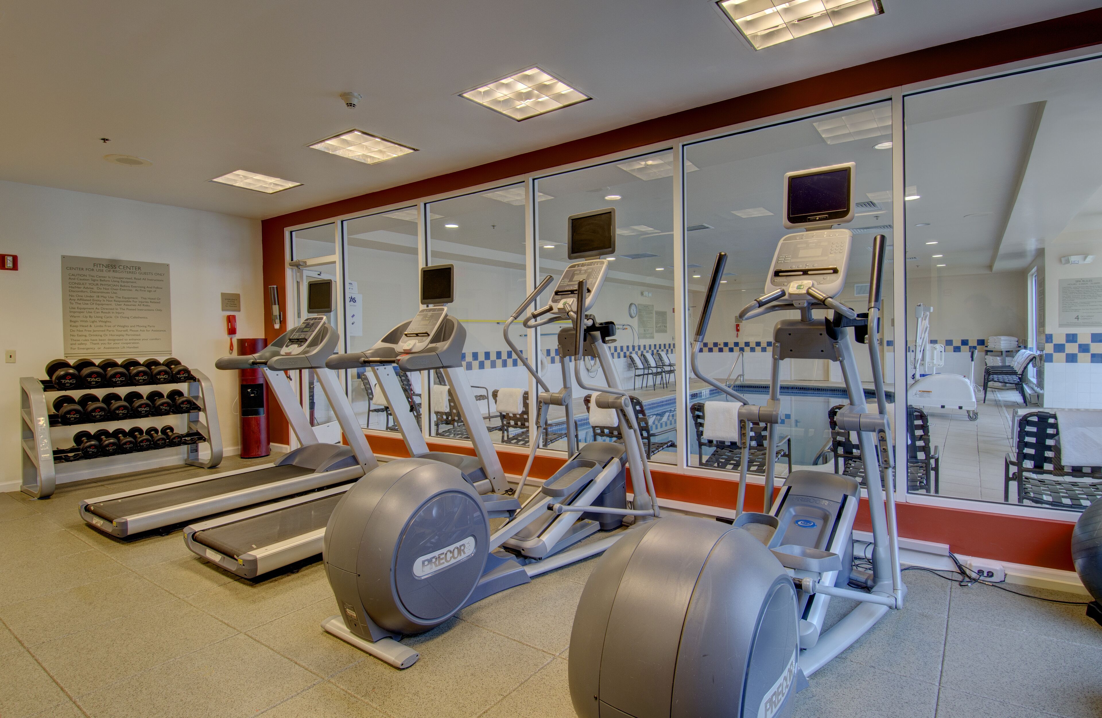A gym with treadmills, elliptical machines, and a weight rack.