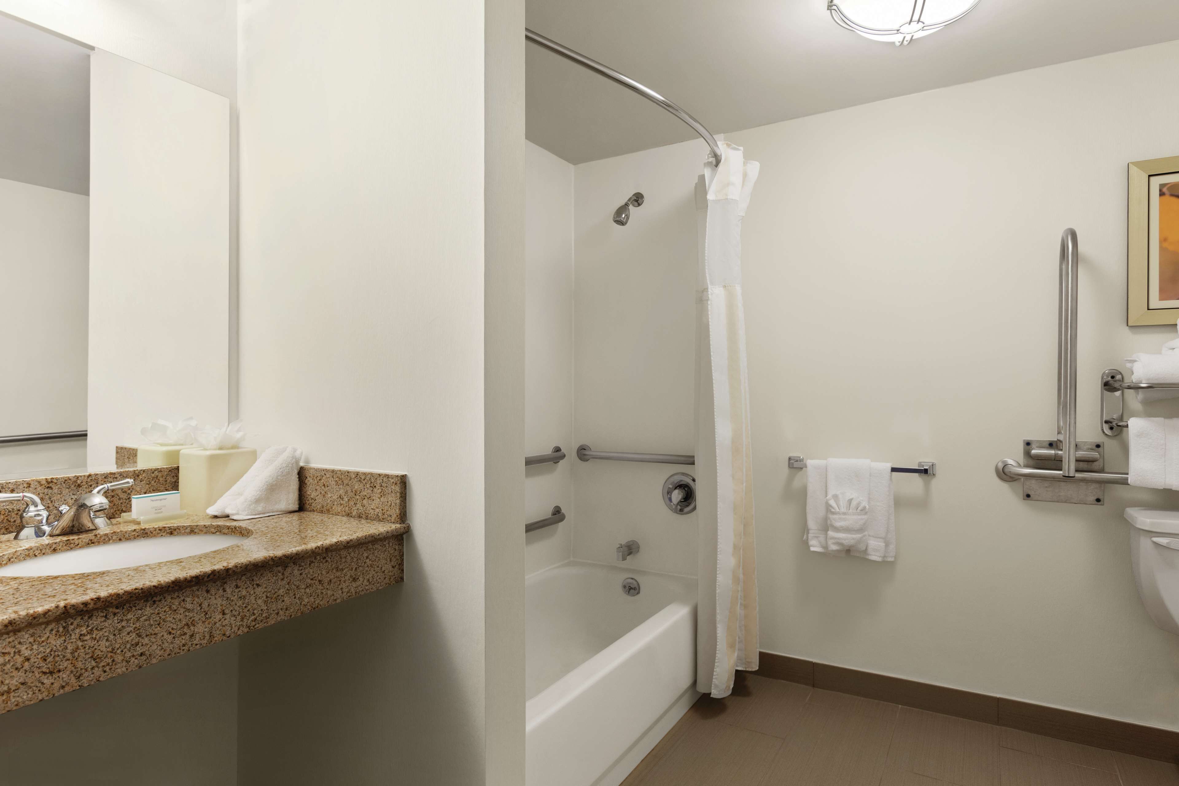 A bathroom with a sink, mirror, bathtub, shower, and toilet.
