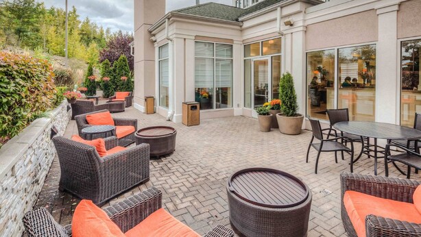 An outdoor patio area with wicker furniture and potted plants. - Hilton Garden Inn Shelton (Shelton)