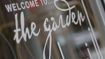 A close-up of a sign with the text "WELCOME TO... the garden!"