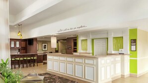 A modern hotel lobby with a reception desk, seating area, and a kitchen in the background. - Hilton Garden Inn Shelton (Shelton)
