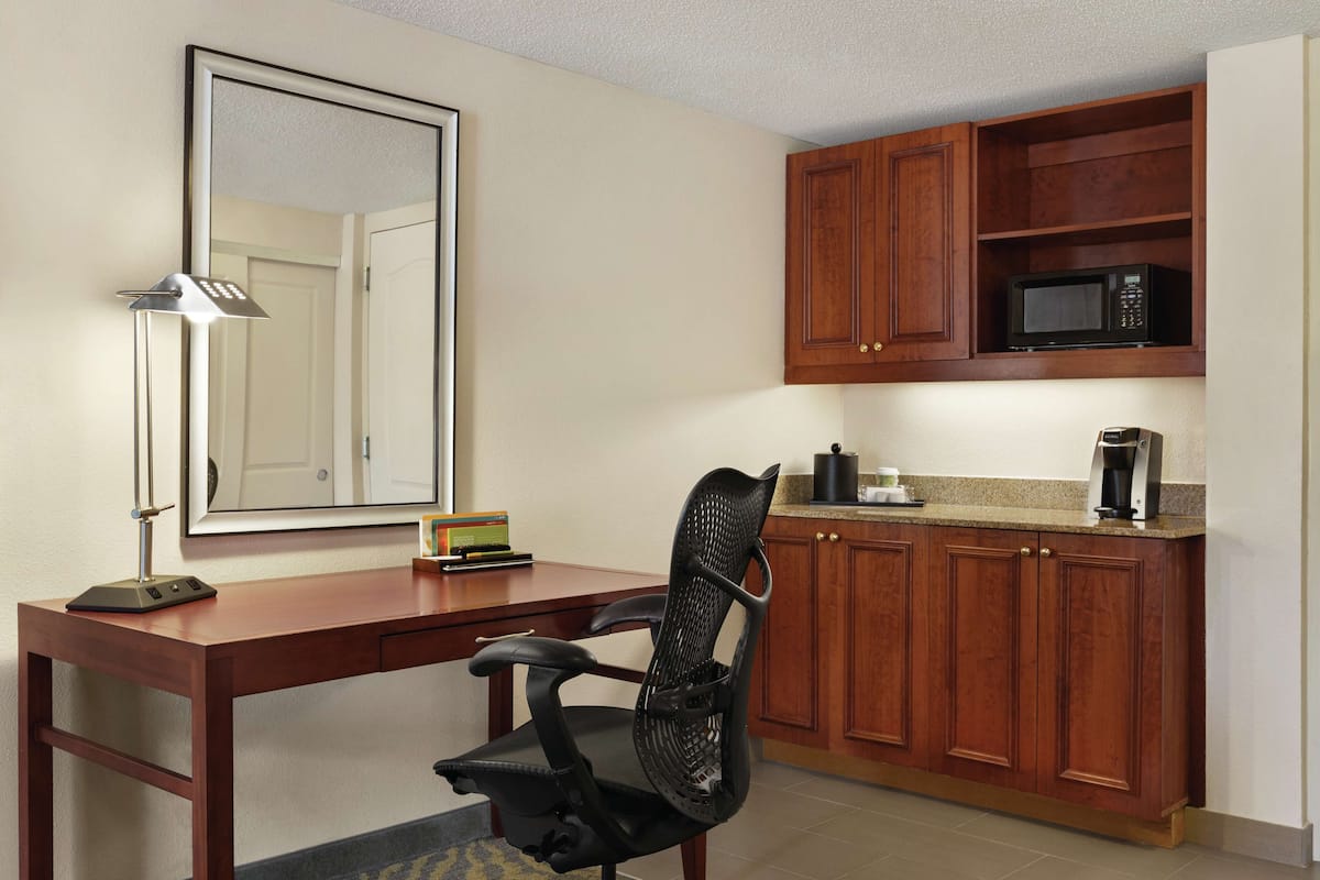 A compact kitchen with wooden cabinets, a microwave, and a coffee maker.