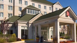 A hotel with a modern design, featuring a central entrance with a covered area and a green roof. - Hilton Garden Inn Shelton (Shelton)
