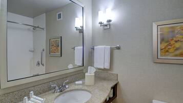 Un baño con un espejo grande, un lavabo, un inodoro y un perchero para toallas.