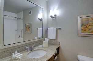 A bathroom with a large mirror, a sink, a toilet, and a towel rack.