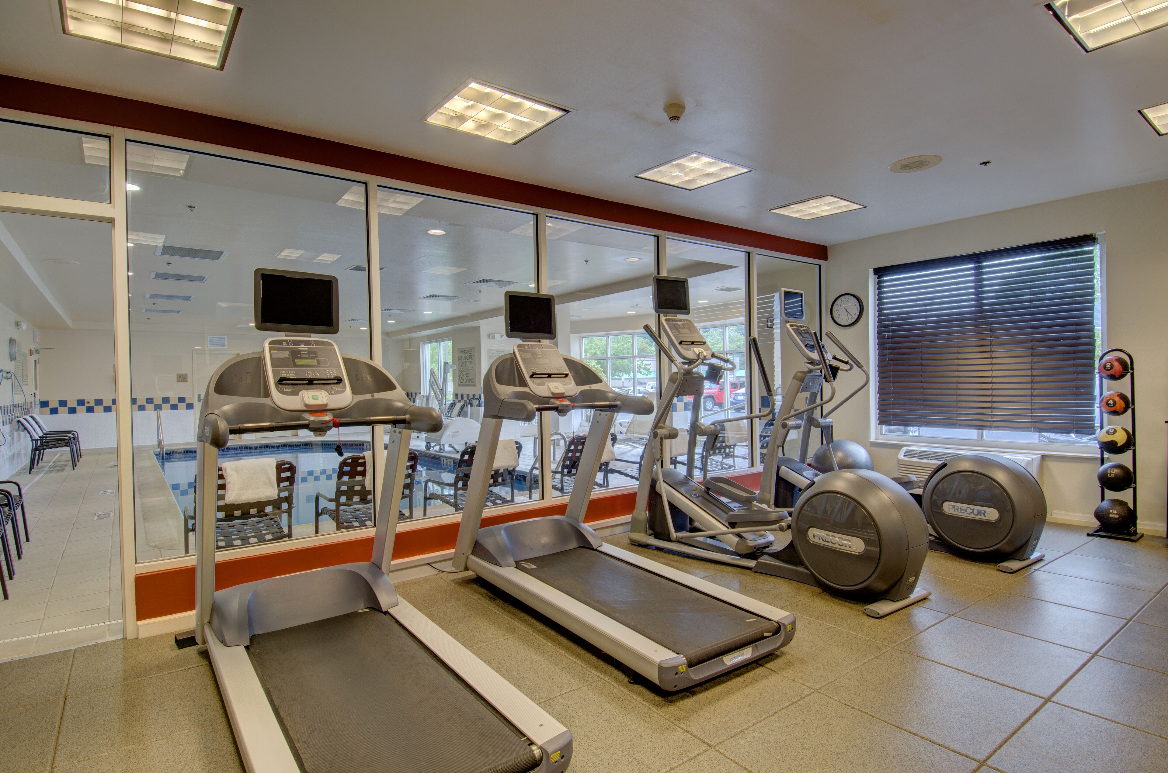 Un gimnasio con cintas de correr, elípticas y máquinas de pesas.