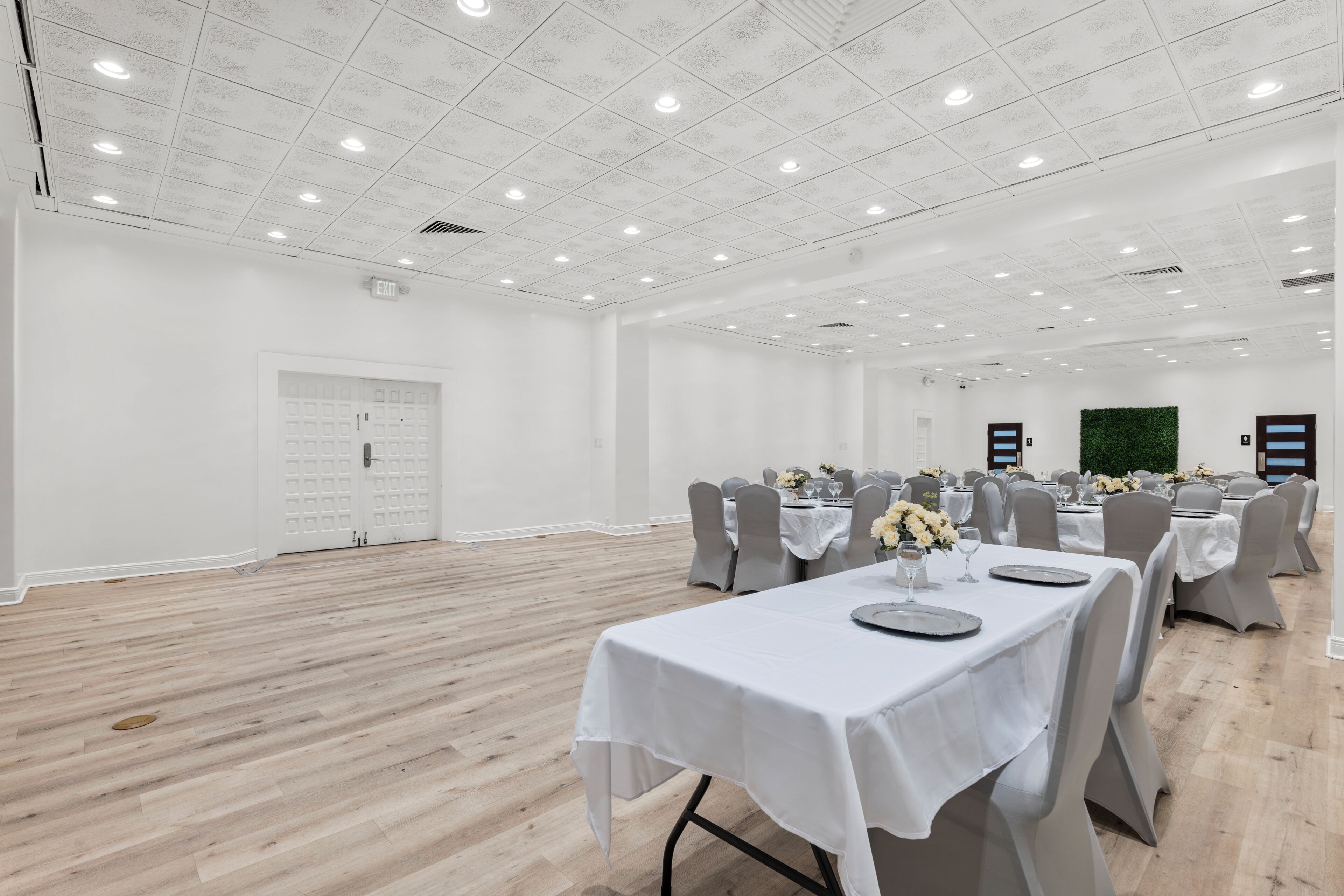 A spacious conference room with white walls, a wooden floor, and multiple tables set up for a meeting.
