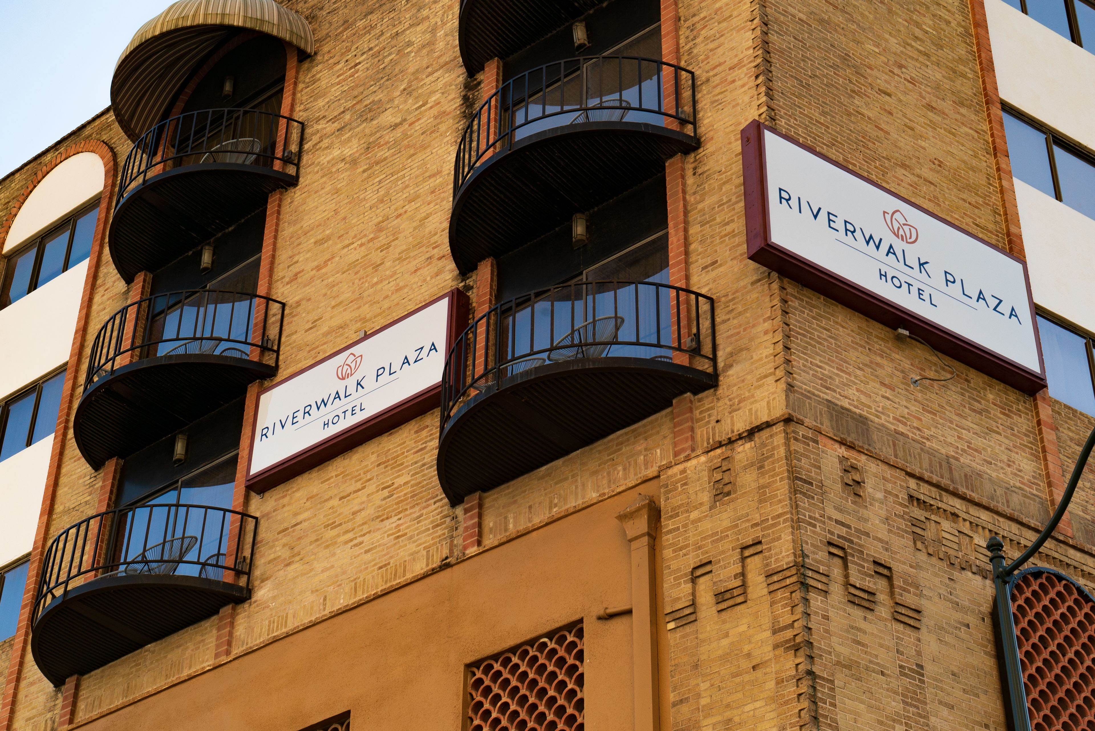 Un bâtiment en briques doté de balcons et de panneaux indiquant l’hôtel Riverwalk Plaza.