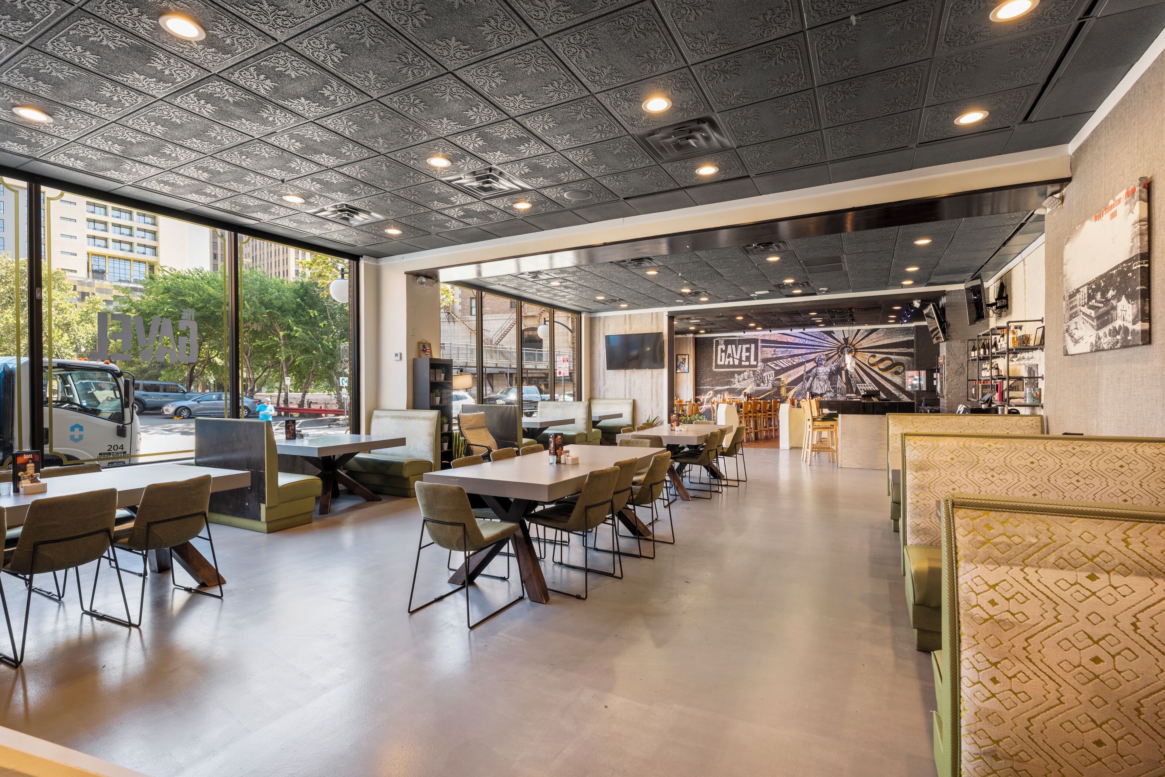 A modern restaurant with a high ceiling, large windows, and a variety of seating arrangements.