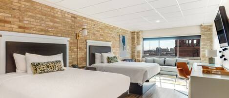 A hotel room with two beds, a sofa, a desk, and a TV.