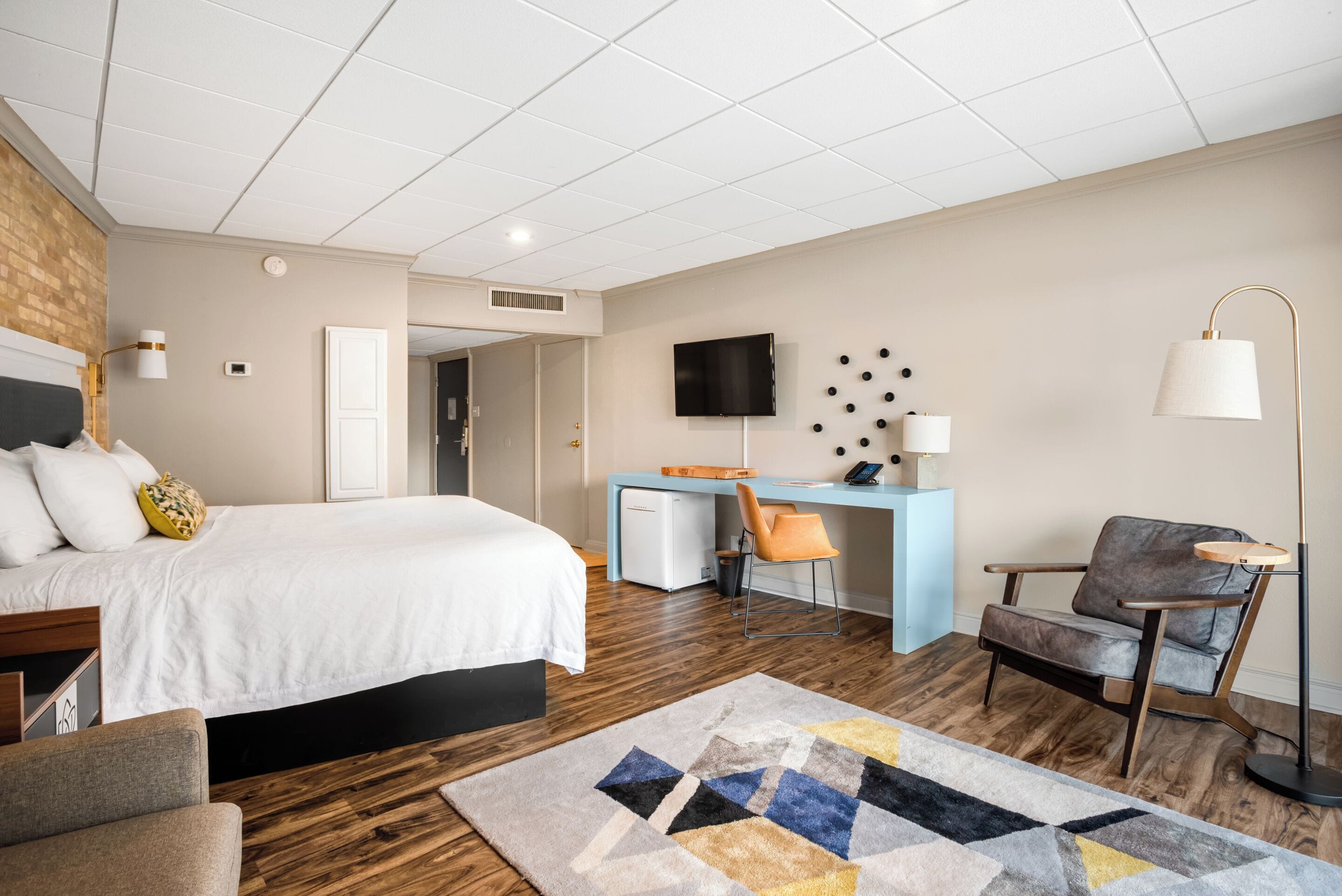 Une chambre d’hôtel moderne, dotée d’un grand lit, d’un bureau, d’une chaise et d’un téléviseur fixé au mur.