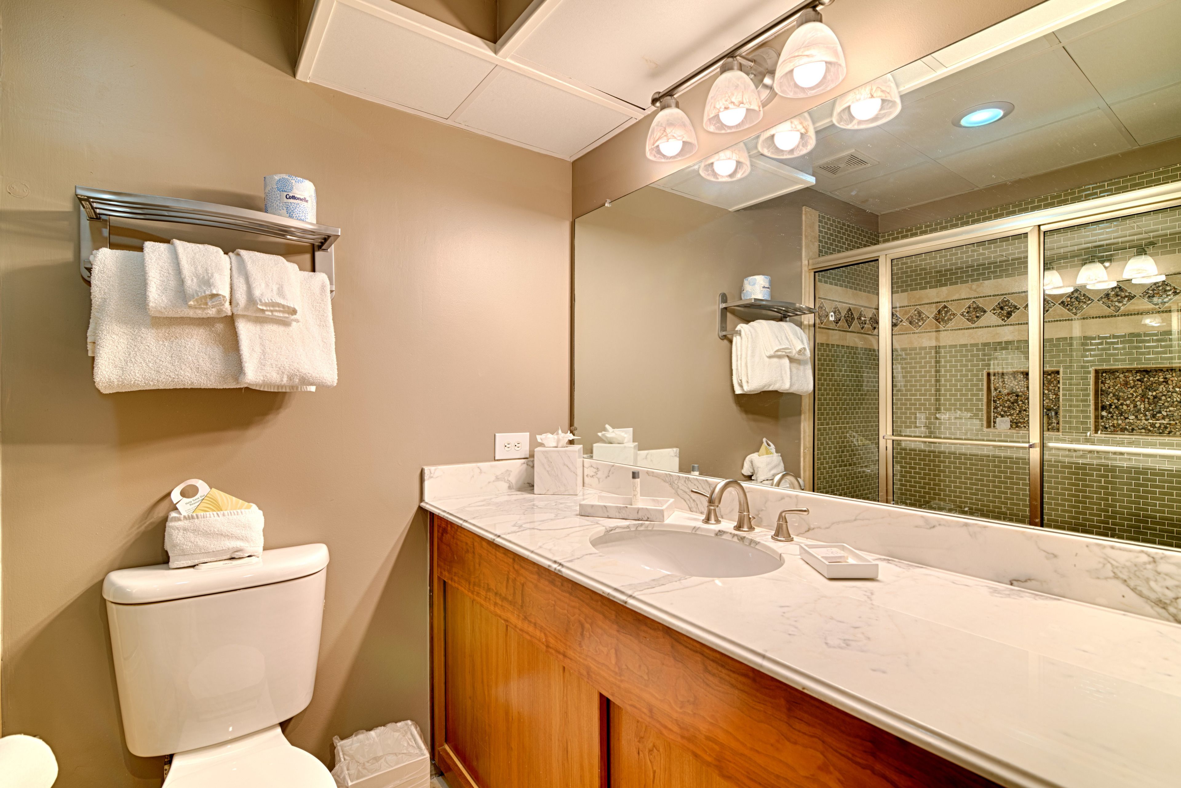 A bathroom with a marble sink, wooden vanity, and a large mirror.