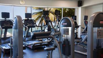 Un gimnasio con diversos equipos de ejercicio, incluyendo cintas de correr y máquinas de pesas, dispuesto en un espacio amplio.