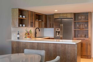 A modern kitchen with wooden cabinets, a stainless steel refrigerator, and a white countertop.