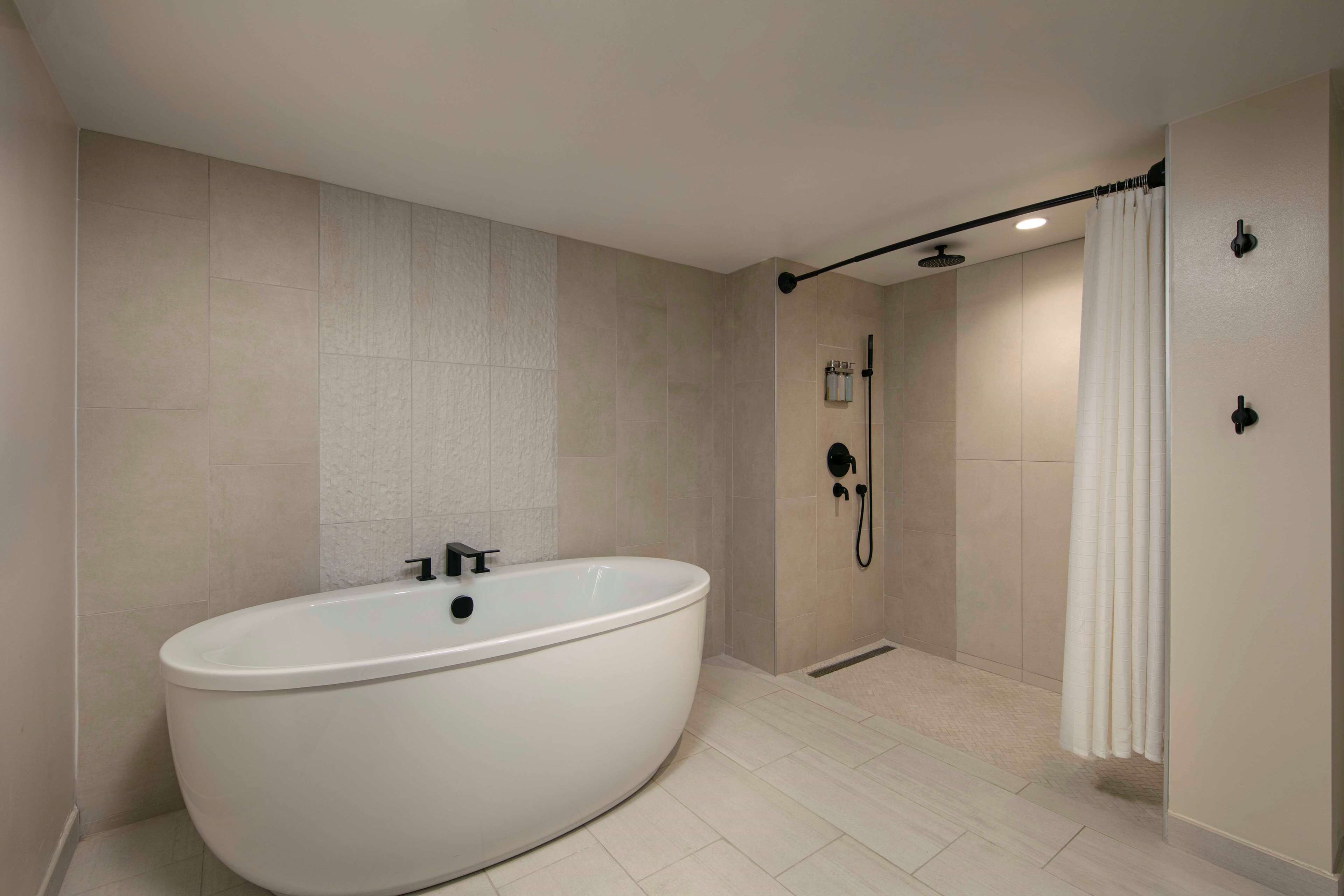 A modern bathroom with a freestanding bathtub, a shower area with a curtain, and a wall-mounted towel rack.