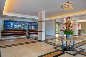 A lobby with a reception desk, a chandelier, and a potted plant.