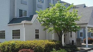 A multi-story residential building with a symmetrical facade, large windows, and a central entrance. - Motel 6 Charlotte, NC - University (Charlotte)