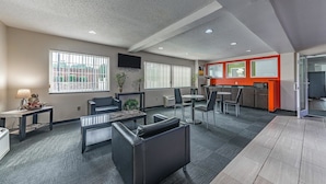 A modern office space with a meeting area, a kitchenette, and a TV mounted on the wall. - Motel 6 Charlotte, NC - University (Charlotte)