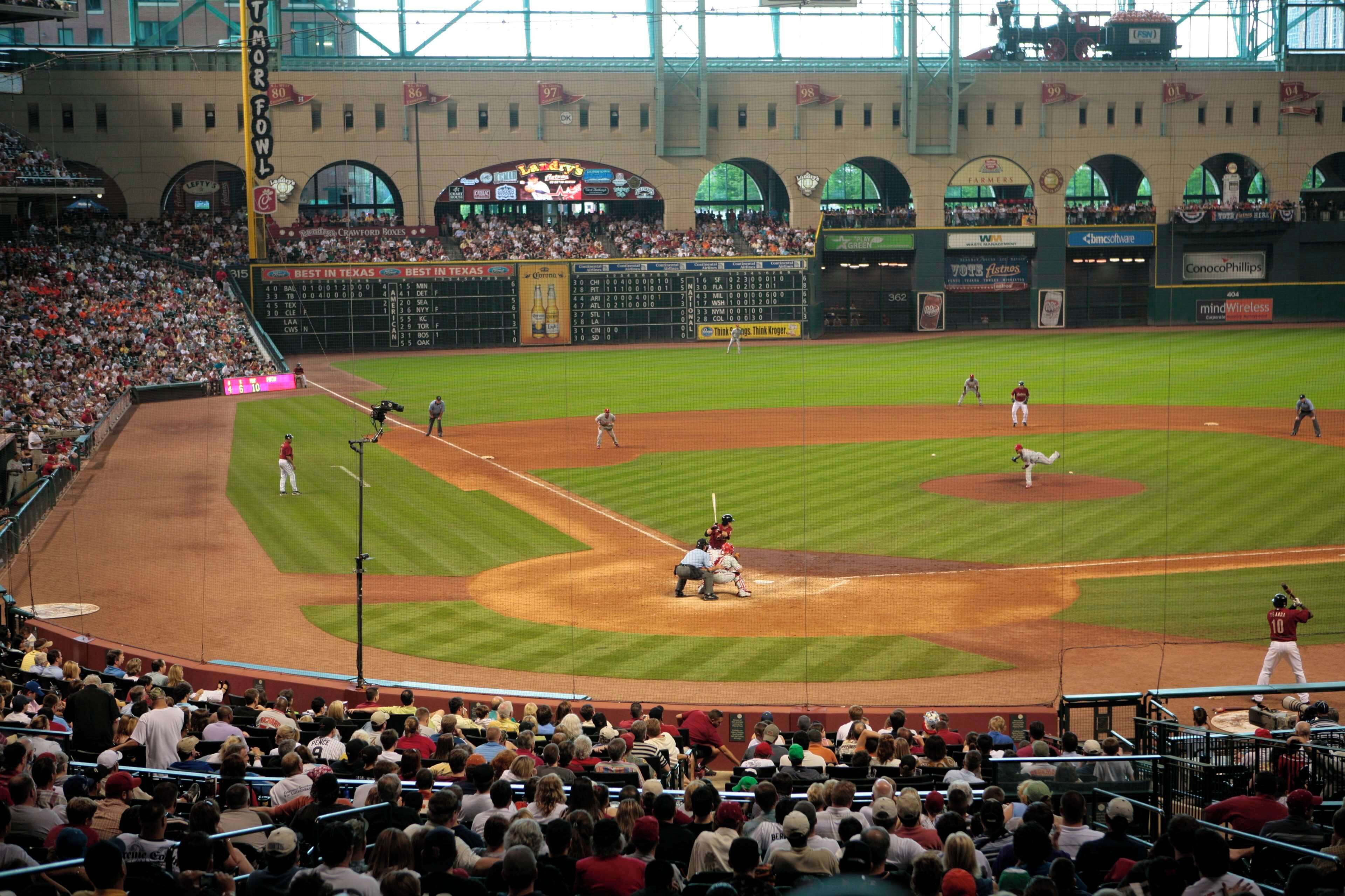 A baseball stadium with a large crowd, multiple levels of seating, and a scoreboard.