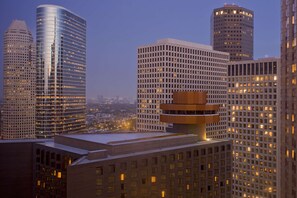 A cityscape with high-rise buildings, including a distinctive building with a rounded top and another with a grid-like facade.