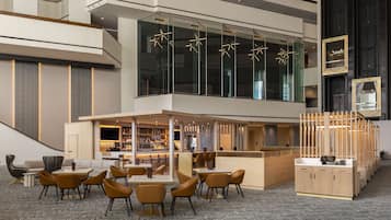 A modern hotel lobby with a bar area, seating, and a staircase.