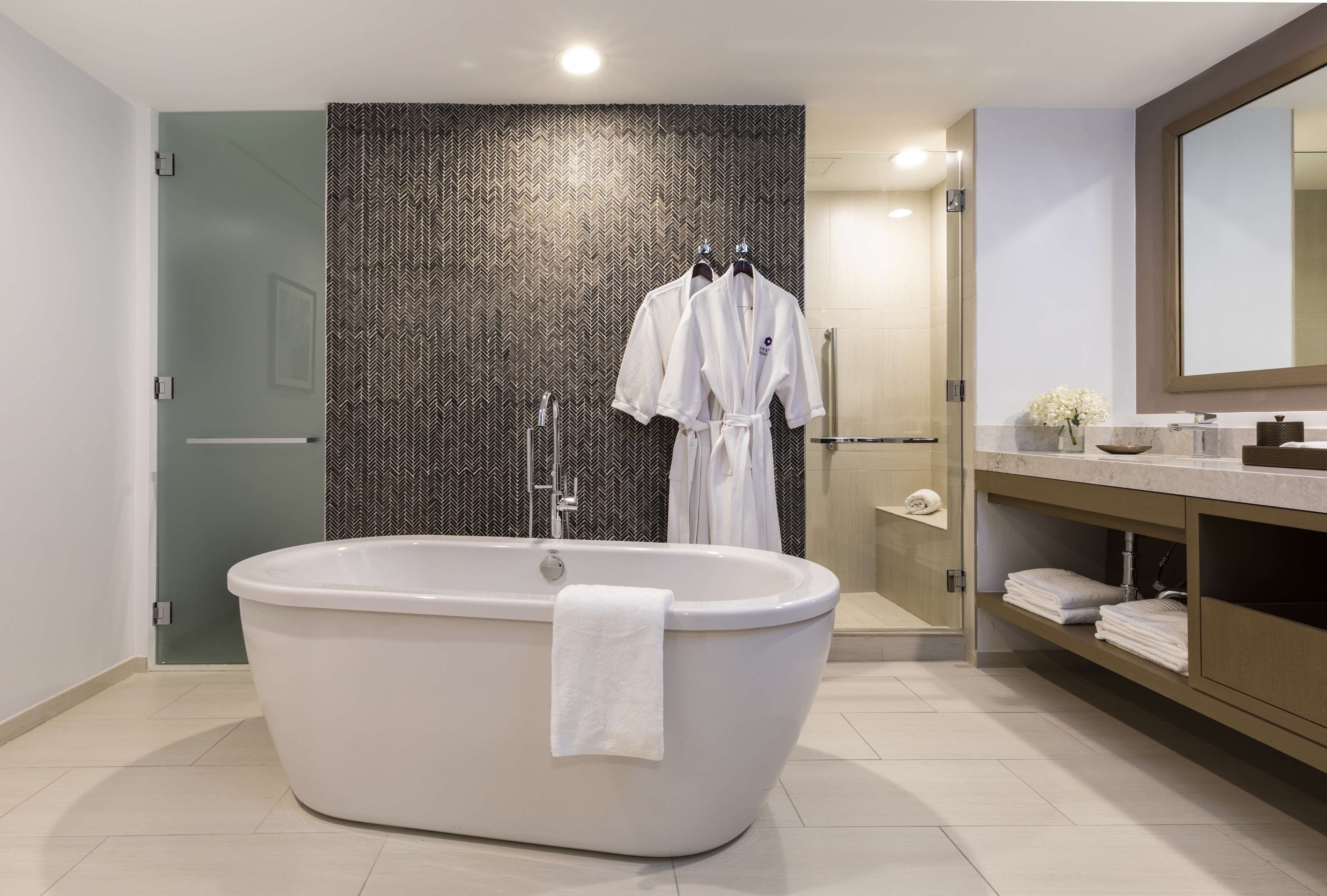 Ein modernes Badezimmer mit einer freistehenden Badewanne, einer Duschkabine aus Glas sowie einem Waschtisch mit Spiegel und Handtuchhalter.