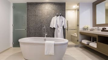 Ein modernes Badezimmer mit einer freistehenden Badewanne, einer Duschkabine aus Glas sowie einem Waschtisch mit Spiegel und Handtuchhalter.