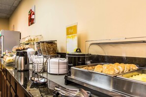 A buffet setup with various food items, a hot sign, and kitchen appliances.