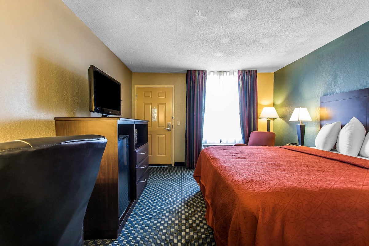 A hotel room with a bed, a TV, a desk, and a chair.