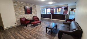 En lobby på Red Roof Inn med en vägg av sten, röda sittmöbler och ett stort fönster.